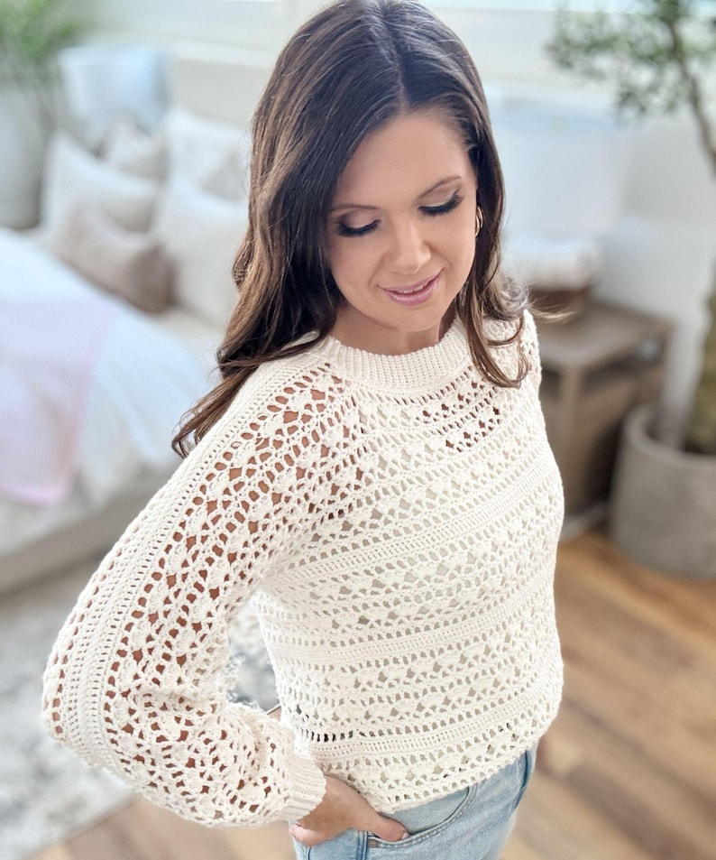 K&ouml;nnte beinhalten: Cremefarbener H&auml;kelpullover mit langen &Auml;rmeln. Der Pullover hat ein strukturiertes, offen gewebtes Design und einen gerippten Ausschnitt und B&uuml;ndchen. Das Model tr&auml;gt eine blaue Jeans.