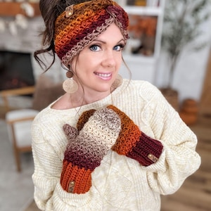 May include: A crocheted headband and mittens set in a fall color palette of orange, burgundy, and cream. The headband features a button detail, and the mittens have a matching design. The set is handmade and suitable for cold weather.