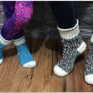 May include: Two pairs of knitted socks, one pair is blue and white, the other pair is gray and white.