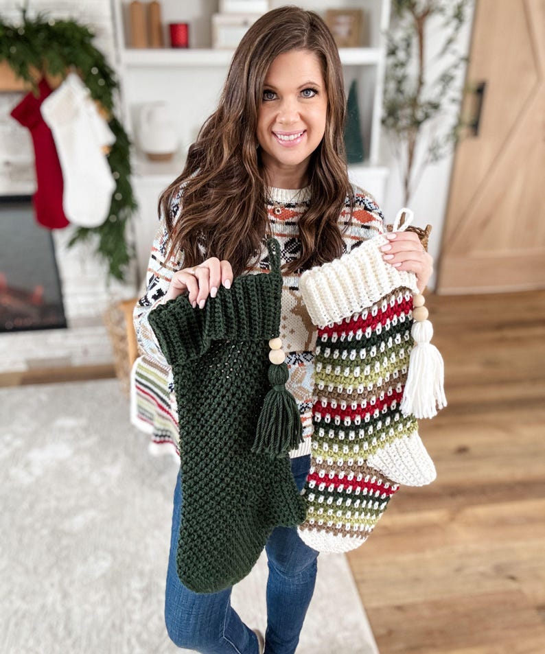 May include: Two handmade Christmas stockings. One is dark green with a tassel and wooden bead detail. The other is striped with white, red, green, and brown. Both are crocheted and have a loop for hanging.
