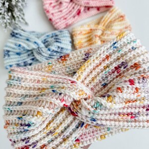 May include: Four crocheted headbands in different colors and patterns. The headbands are made with a chunky yarn and have a twisted knot design. The colors include pink, blue, yellow, and white.
