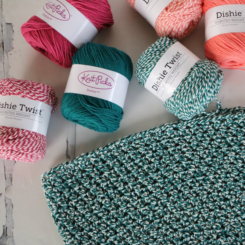 May include: Four balls of yarn in different colours: teal, pink, coral, and white and red striped. The yarn is labelled "Knit Picks Dishie Twist Worsted Weight".