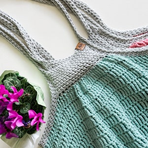 May include: A gray and teal crocheted tote bag with a brown leather tag that says "Jada".