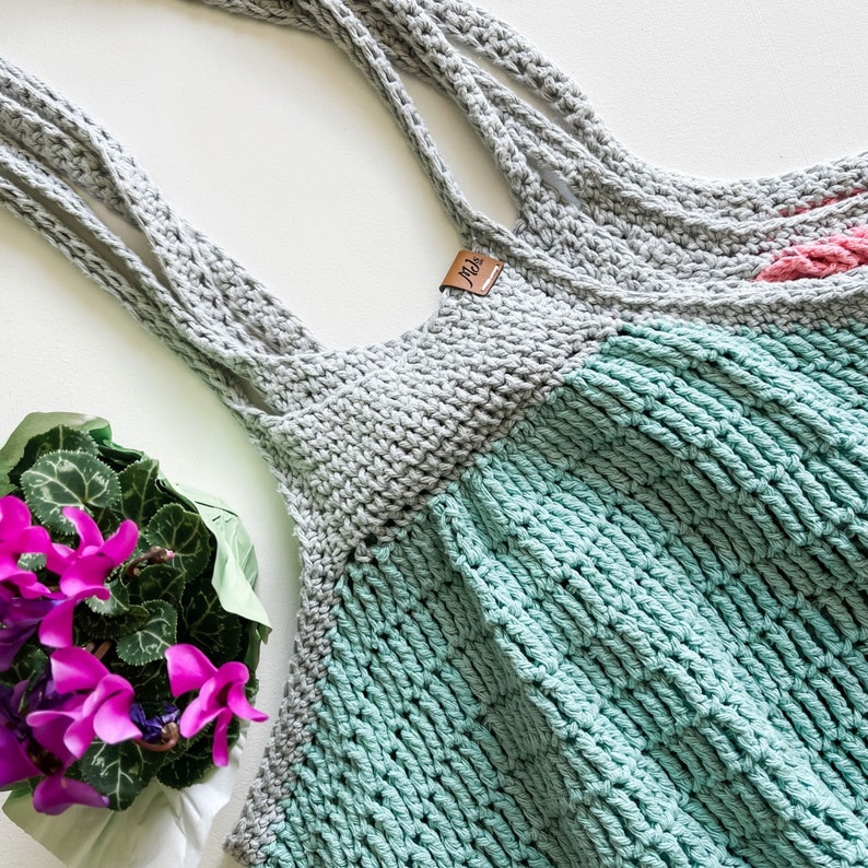 May include: A gray and teal crocheted tote bag with a brown leather tag that says "Jada".