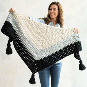 May include: A triangular crocheted shawl with black, grey, and beige stripes and tassels on the ends.
