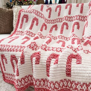 K&ouml;nnte beinhalten: Eine wei&szlig;-rote H&auml;keldecke mit einem Zuckerstangenmuster. Die Decke hat einen roten Rand und dekorative Elemente. Ideal f&uuml;r die Weihnachtszeit.