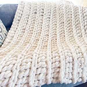 Peut inclure: Une couverture en tricot &eacute;pais de couleur blanche avec une texture douce et moelleuse. La couverture est faite de fil &eacute;pais et a un design simple et &eacute;l&eacute;gant.