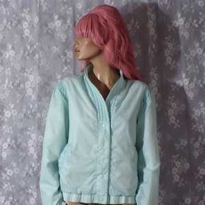 May include: A light blue jacket with a button closure and a ribbed hem. The jacket is made of a lightweight fabric and has a casual style.