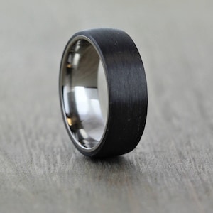 Black mans wedding ring. Polished titanium sleeve with a matte/brushed black Carbon Fibre exterior. brushed mans wedding band, lightweight and waterproof, an alternative wedding ring that is hard wearing and modern