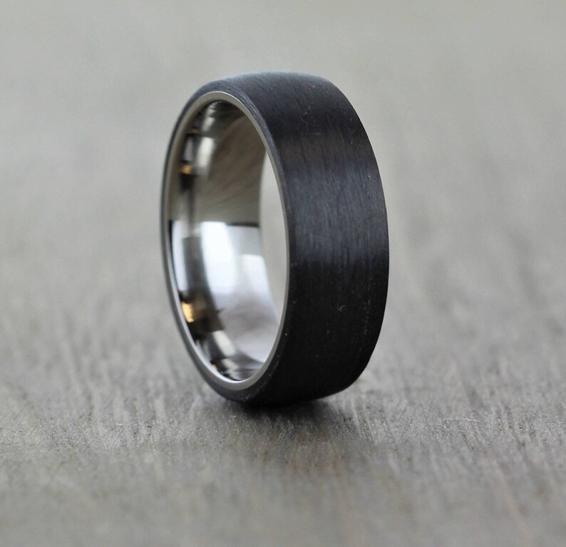 Black mans wedding ring. Polished titanium sleeve with a matte/brushed black Carbon Fibre exterior. brushed mans wedding band, lightweight and waterproof, an alternative wedding ring that is hard wearing and modern