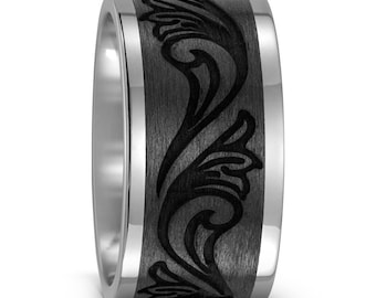 Op de afbeelding: Een zwarte en zilveren trouwring met een decoratief patroon. De ring is gemaakt van titanium en heeft een geborstelde afwerking.