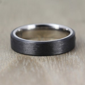 May include: A black brushed metal ring with a silver band around the edge.