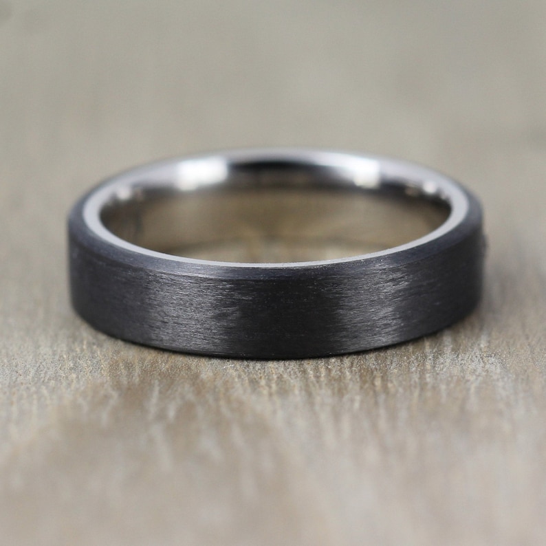 May include: A black brushed metal ring with a silver band around the edge.
