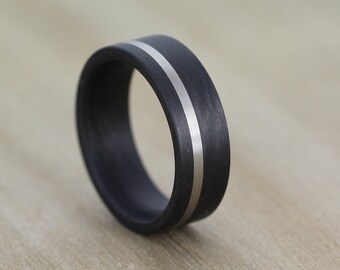 May include: A black carbon fiber ring with a silver inlay. The ring is a simple design with a smooth finish.