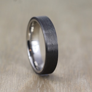 May include: A black and silver wedding band with a brushed finish.