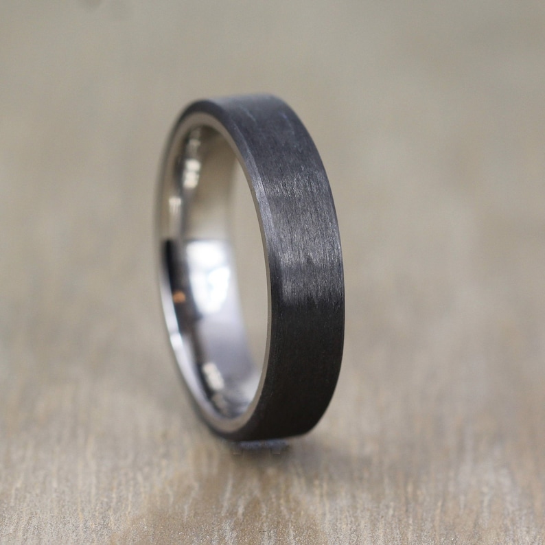 May include: A black and silver wedding band with a brushed finish.