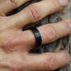 the best mans black wedding ring band 2023, Polished titanium sleeve in comfort fit. Covered in Matte/brushed black Carbon Fibre. 6 millimetres wide 7mm Court shape and comfort fin. dome shape of the ring sits with a low profile on the finger