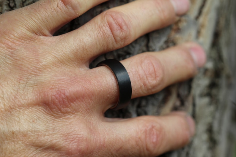 the best mans black wedding ring band 2023, Polished titanium sleeve in comfort fit. Covered in Matte/brushed black Carbon Fibre. 6 millimetres wide 7mm Court shape and comfort fin. dome shape of the ring sits with a low profile on the finger