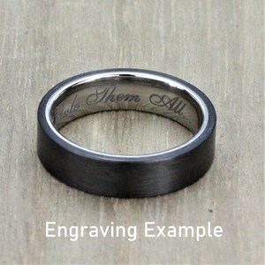 May include: A black and silver wedding band with an inscription that reads "Them All". Engraving example.