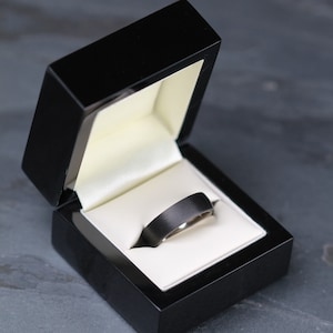 mens black wedding ring band in titanium and carbon fibre. Flat court with a comfort fit inside the 10mm wide ring is inlayed with hand wound carbon fiber. court shape, low dome shape