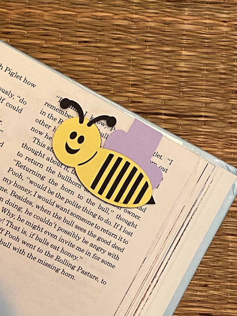 May include: A yellow and black paper bee bookmark with a smiling face. The bookmark is placed on a page of a book with the text "Returning the horn to the bull..."