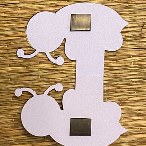May include: A white felt craft cutout of a caterpillar with two black magnetic squares attached to the back.
