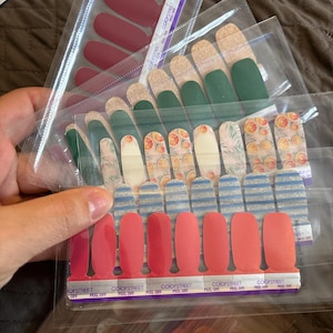 May include: Assortment of Color Street nail polish strips in various colors and patterns. Includes solid burgundy, green, orange floral, blue striped, and shades of pink. Each strip is in a clear plastic package.
