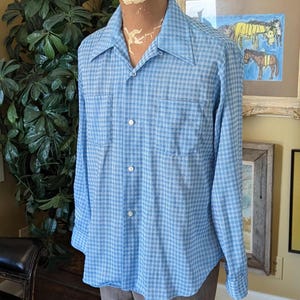 May include: A blue and white checkered long-sleeve shirt with a collared neckline and button closure.