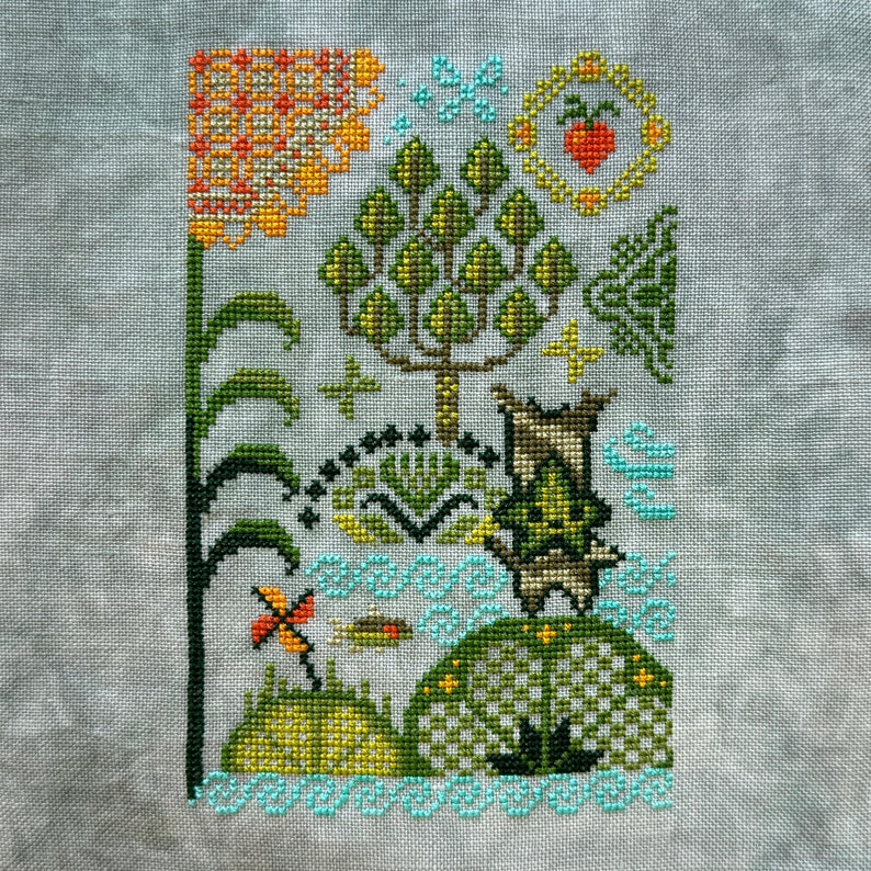 K&ouml;nnte beinhalten: Kreuzstichmuster mit einer fantasievollen Gartenszene mit einem Baum, einem Schmetterling, einer Libelle und einer Blume. Das Design ist in Gr&uuml;n-, Orange-, Gelb- und Blaut&ouml;nen gestickt.