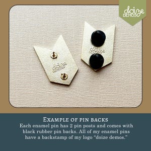May include: Two gold-colored enamel pin backs with black rubber pin backs. Each pin has two posts. The pins are shaped like arrows. The text "doize demos" is stamped on the back of each pin.