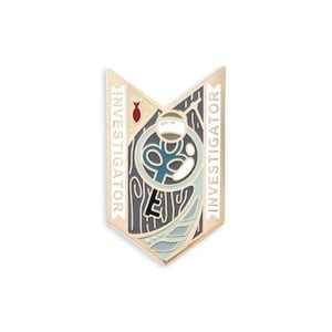 Puede incluir: Pin de esmalte de color dorado con un diseño azul, verde y blanco. El pin presenta una imagen estilizada de una persona sosteniendo una llave. Las palabras "INVESTIGATOR" están escritas a ambos lados del diseño.