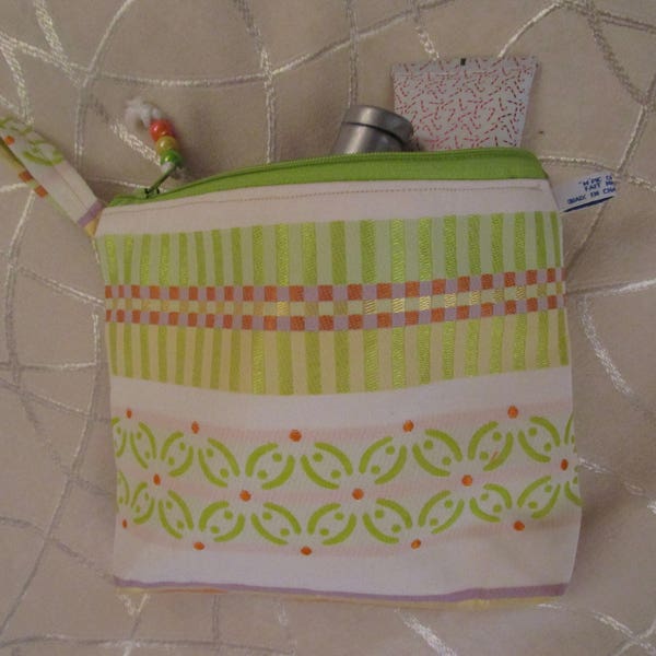 trousse en tissu de coton satiné jacquard, écrue avec des dessins verts, oranges et dorés, doublée jaune