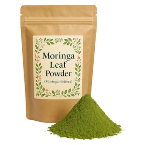 May include: A brown paper bag with a label that reads "Moringa Leaf Powder (Moringa oleifera)". The bag is sitting on a white surface next to a pile of green powder.