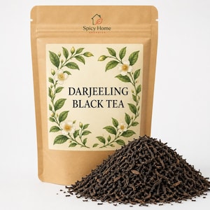 May include: A brown paper pouch of Spicy Home Organics Darjeeling Black Tea. The label features a botanical illustration of white flowers and green leaves framing the text. A pile of loose, dark brown tea leaves sits in front of the pouch.