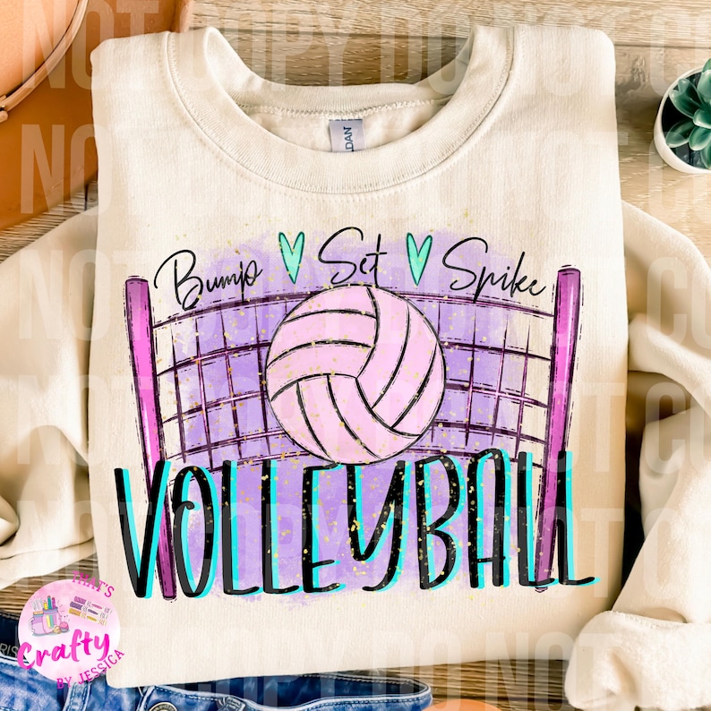 May include: A white sweatshirt with a volleyball design. The design features a volleyball net with a pink volleyball, and the words "Bump Set Spike Volleyball" in a colorful font.