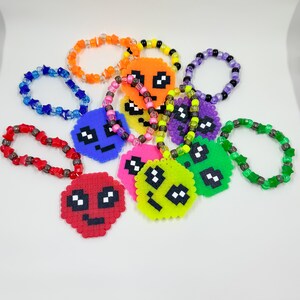 May include: A collection of colorful beaded bracelets with pixelated smiley face charms. The bracelets are made with different colored beads and feature various smiley face designs.