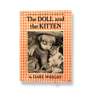 May include: Vintage book cover with the title "The DOLL and the KITTEN" in bold black letters. The cover features a doll and a kitten in a garden setting, with a checkered orange and white border. The author's name, DARE WRIGHT, is at the bottom.