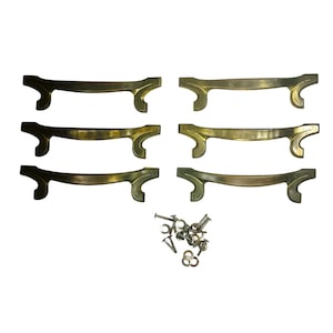 May include: Six brass-toned metal drawer pulls arranged in two columns of three, each featuring a curved central bar and flared, scroll-like ends. A small pile of silver-toned metal screws and circular washers is positioned below the pulls.