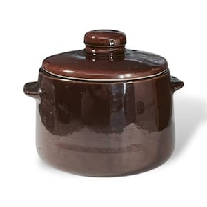 May include: A brown ceramic pot with a lid. The pot has two small handles on either side and a rounded lid with a small knob. The pot is a dark brown color and has a glossy finish. The pot is likely used for cooking or storage.