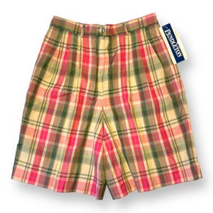 May include: High-waisted shorts featuring a plaid pattern in shades of pink, green, and cream. The shorts have a button closure, belt loops, and a Pendleton brand tag attached to the waistband. The design includes front pleats and side pockets.