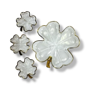 May include: Four-leaf clover-shaped serving dishes. The dishes are clear glass with gold-colored trim and stems. The largest dish is approximately 8 inches in diameter, while the smaller ones are about 4 inches across. The dishes are arranged on a white background.