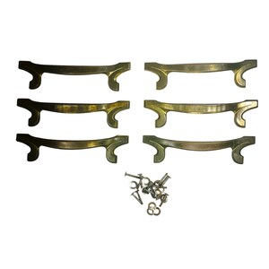 May include: Set of seven antique brass drawer pulls with a curved design. Each pull has a central bar with decorative curved ends. Includes a small pile of screws and washers for installation. Ideal for furniture restoration projects.