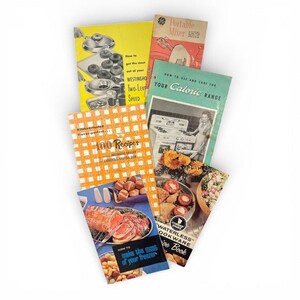 May include: A collection of vintage cookbooks with colorful covers. Titles include "100 Recipes", "How to Use and Care for Your Caloric Range", and "How to Make the Most of Your Freezer". The cookbooks feature illustrations of food and kitchen appliances.