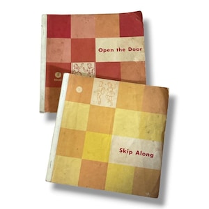 May include: Two vintage softcover books with checkered covers. The top book is red and orange with the text Open the Door and a small illustration. The bottom book is yellow and orange with the text Skip Along and a small illustration of two children.