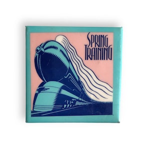 May include: A white ceramic mug with a black handle and the text "But First, Coffee" in a bold, black font. The mug is set against a blurred background, suggesting a cozy setting.