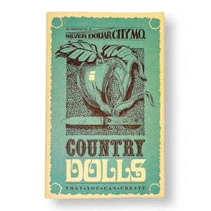 May include: Vintage book cover with a teal background and a distressed, aged appearance. The cover features a graphic of an apple with corn and a knife, with the text "COUNTRY DOLLS" and "THAT YOU CAN CREATE". The text "AS HANDCRAFTED IN SILVER DOLLAR CITY MO" is also present.