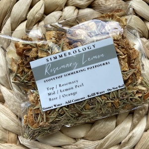 Puede incluir: Una bolsa transparente llena de hierbas secas y c&aacute;scaras de c&iacute;tricos, etiquetada como "Rosemary Lemon" de Simmerology. La bolsa contiene romero, c&aacute;scara de lim&oacute;n y naranja. El texto de la etiqueta dice "Popurr&iacute; para estufa".