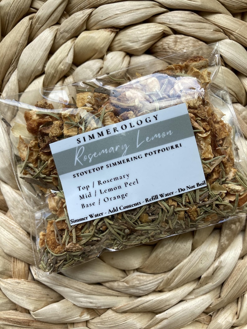 Puede incluir: Una bolsa transparente llena de hierbas secas y c&aacute;scaras de c&iacute;tricos, etiquetada como "Rosemary Lemon" de Simmerology. La bolsa contiene romero, c&aacute;scara de lim&oacute;n y naranja. El texto de la etiqueta dice "Popurr&iacute; para estufa".