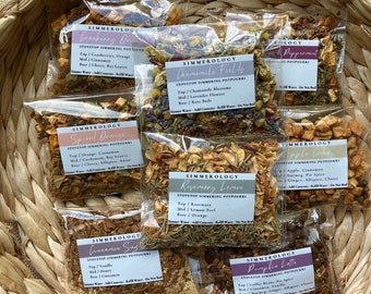 May include: A woven basket filled with several clear plastic pouches of stovetop simmering potpourri. Each pouch has a label with the name of the scent, such as "Cranberry Orange" and "Pumpkin Latte". The potpourri includes dried herbs, spices, and fruit.
