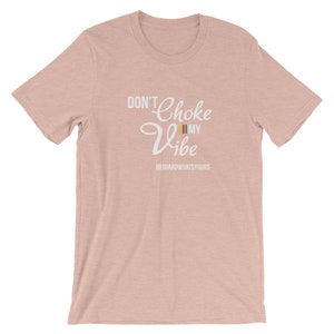 May include: A pink t-shirt with the text "Don't Choke My Vibe" in white with a small multi-colored flag graphic. The text "#GUARDWHATSYOURS" is below the main text.